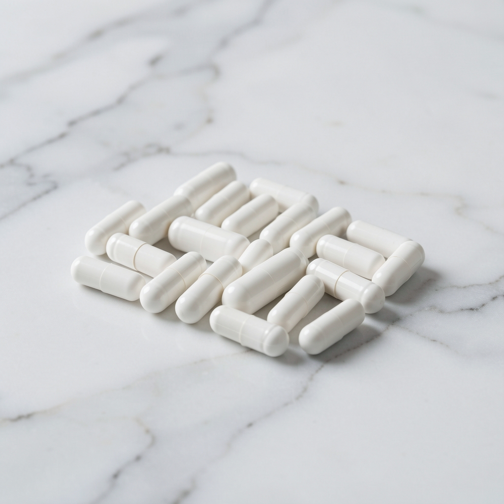 Supplement capsules arranged in a neat row on pale surface with minimal shadow, editorial vitamin product photograph